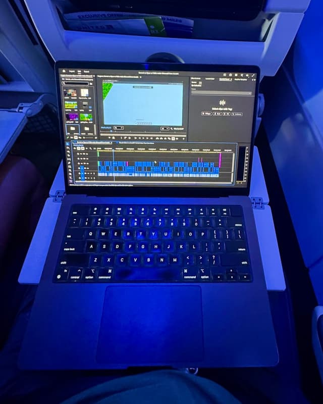Silas's laptop on an airplane tray table with a video editing timeline open